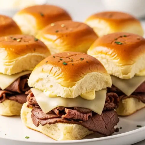 Roast beef and swiss sliders with melted cheese on soft toasted rolls.